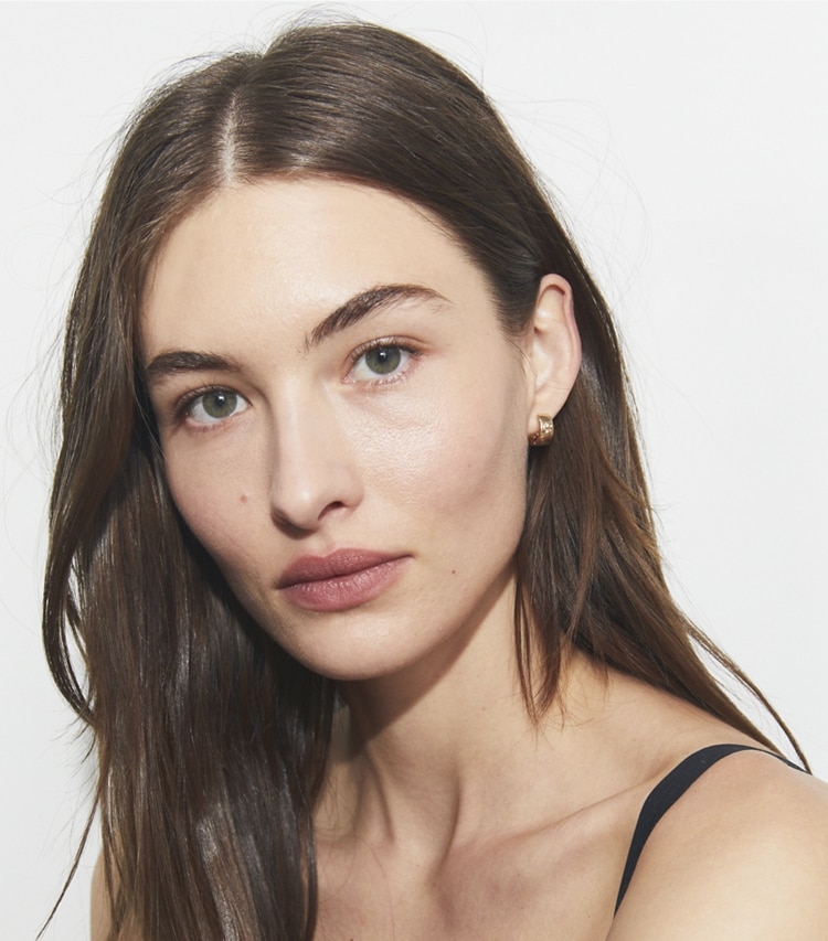 Tory Burch designer earrings Icon Huggie Earrings in Tory Gold accessory on model