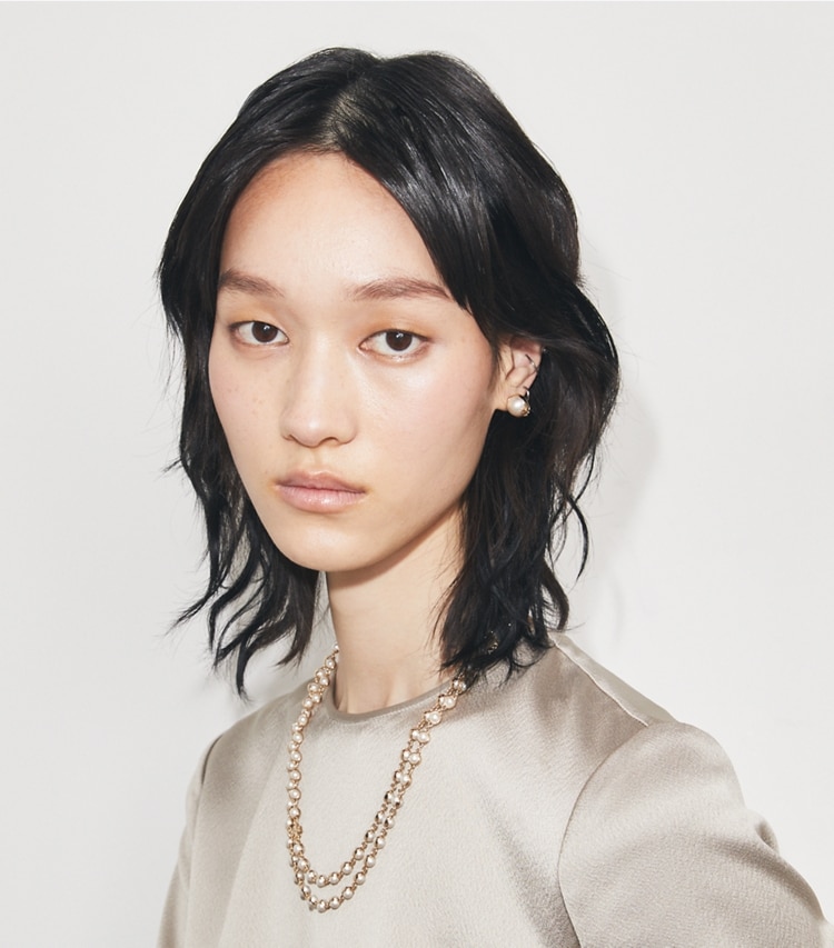 Tory Burch designer halsketten Lange Perlenkette in Light Brass / Pearl accessory on model