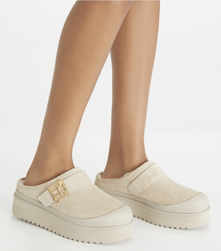 Tory Burch designer flats Mellow Shearling Platform Mule in CALCARE / GOLD accessory on model