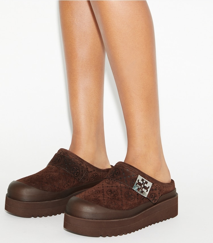 Tory Burch diseñador zapatos planos Mules de plataforma de borreguillo Mellow con monograma de T en DARK COCOA T MONOGRAM / SILVER accesorio en el modelo