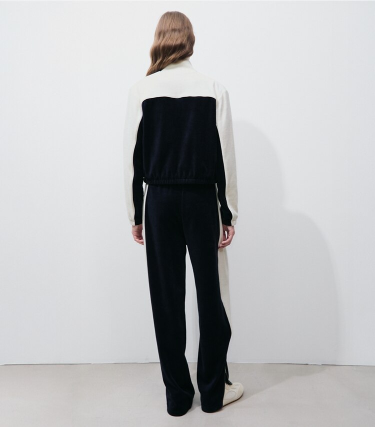 Tory Burch designer bas Pantalon d’entraînement en velours à blocs de couleurs dans Medium Navy / New Ivory sur modèle, de dos
