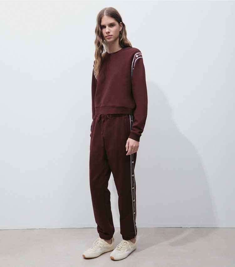 Tory Burch designer bas Pantalon de survêtement en coton bouclette à broderie dans Merlot sur modèle, de face