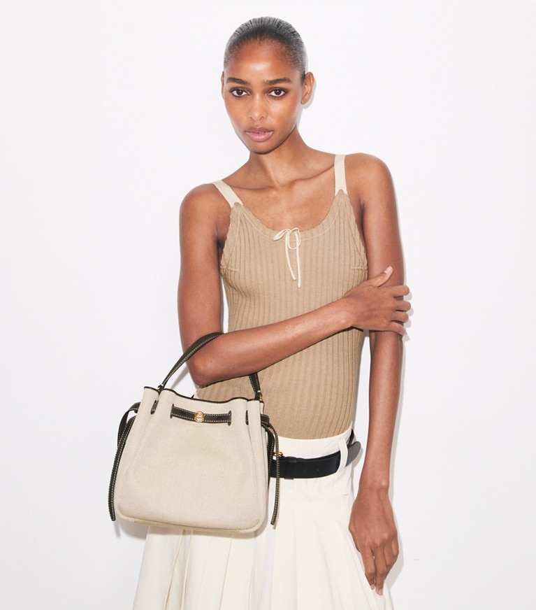 Tory Burch designer crossbody bags Romy Bucket Bag aus Canvas in Dusty Almond/ Bianco White accessory on model