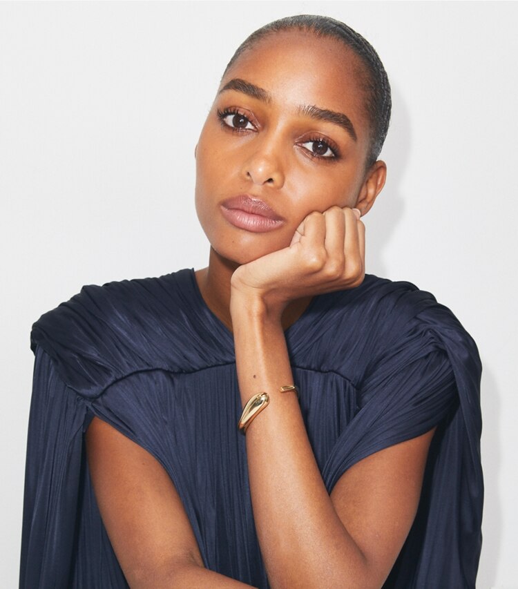 Tory Burch designer armbänder Schmale Armspange mit Piercingdetail in Light Brass accessory on model