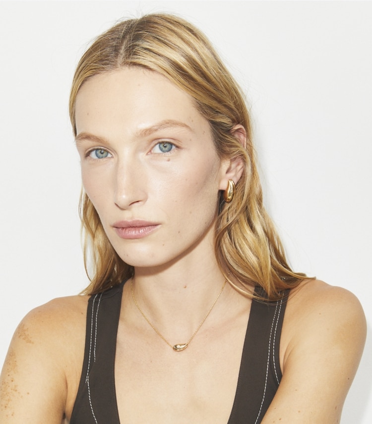 Tory Burch designer ネックレス ウェーブ スモール ペンダント in Light Brass accessory on model
