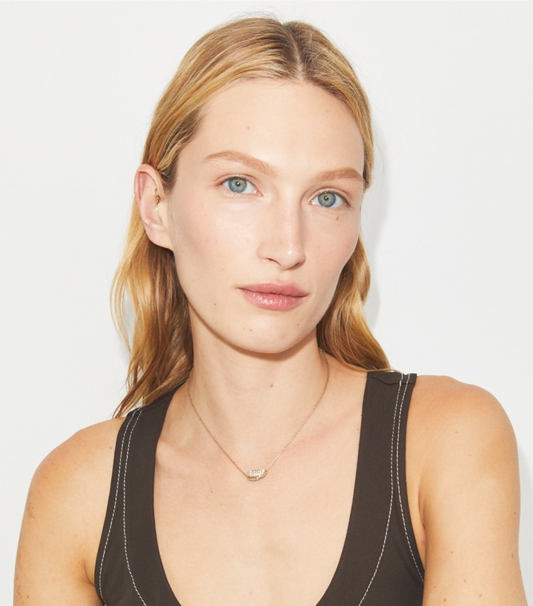 Tory Burch designer necklaces Wave Pavé Pendant in Light Brass / Crystal accessory on model