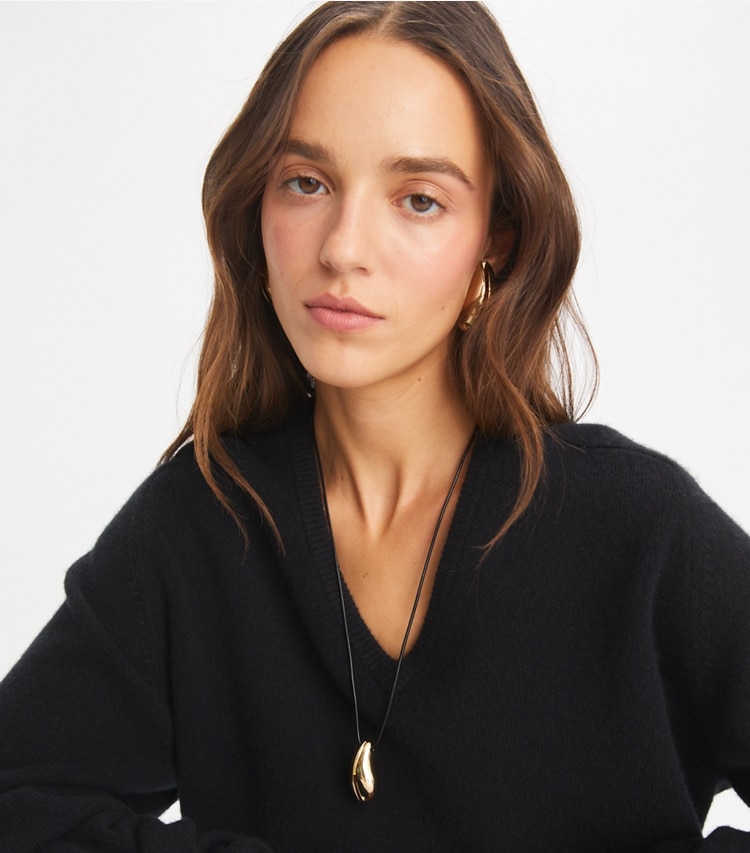 Tory Burch designer necklaces Wave Pendant in Light Brass / Black accessory on model